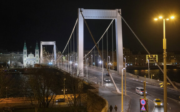 Elevated night view of Elisabeth Bridge crossing the Danube in Budapest, Hungary, with the illuminated Inner City Parish Church near the Pest bridgehead and traffic moving 