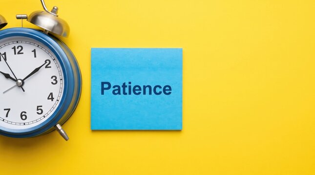 Blue analog alarm clock next to a square blue sticky note with the word patience printed in dark blue text on a solid bright yellow background