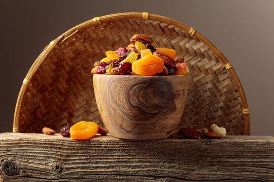 Assorted nuts and dried fruits in wooden dish.