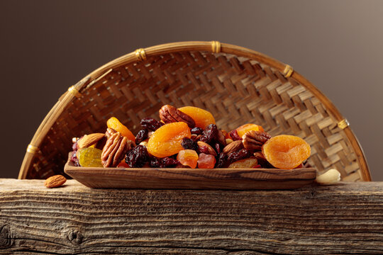 Assorted nuts and dried fruits in wooden dish.
