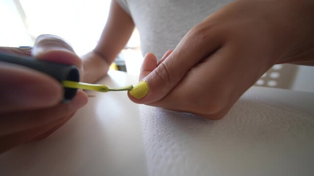 Painting a thumbnail with bright yellow nail polish