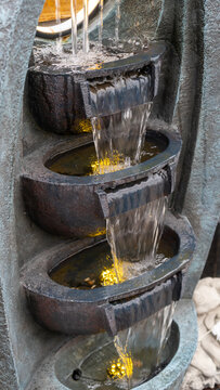A multi-tiered decorative fountain with a cascading stone effect and LED lighting