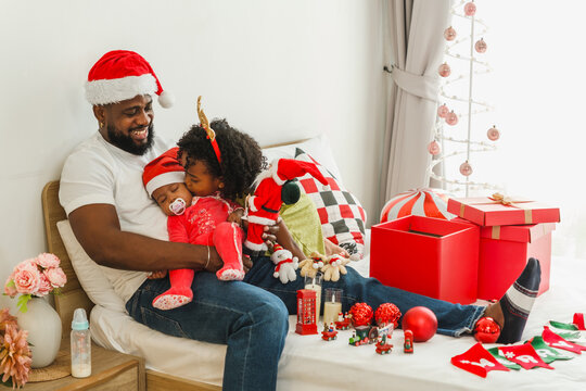 Father and children cuddle together among holiday decorations at home