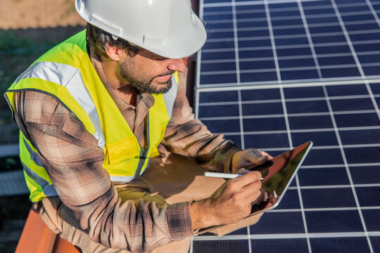 Engineer checking data on tablet by solar panels