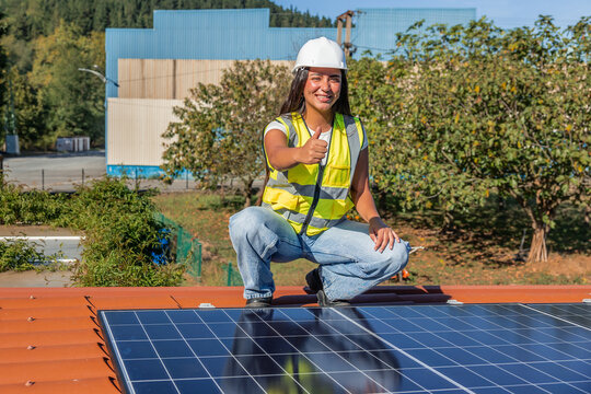 Female solar engineer giving thumbs up installing solar panels