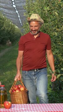 Father and Daughter Walking Through Apple Orchard During Harvest. Farmer father carries freshly picked apples while sharing a warm family moment with his daughter. Family apple orchard.