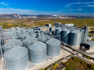 Grain storage silos and processing equipment at an industrial facility near the coast in daylight © DSMT