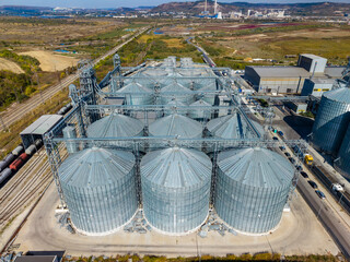 Aerial view of grain storage silos beside railway tracks at an industrial facility in the countryside © DSMT