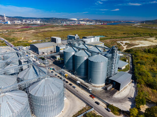 Grain storage silos and processing buildings beside a road in an industrial area during daytime © DSMT