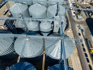 Aerial view of grain silos and conveyor systems at an industrial storage facility during daytime © DSMT