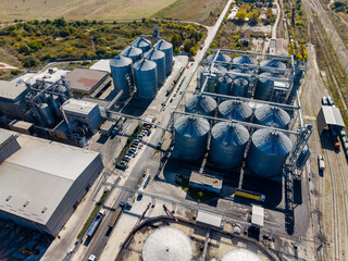 Aerial view of grain silos and rail lines at an industrial storage facility during daylight © DSMT