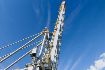 Large Port Crane Rising High Against a Bright Blue Daytime Sky © Tom