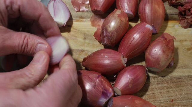 Stockholm, Sweden A cook cuts and peels shallots or onions on a wooden board with a large knife. 