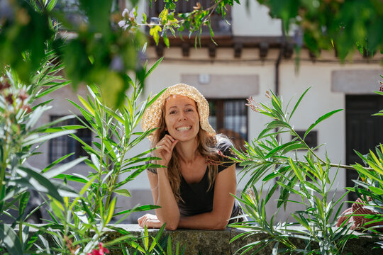Happy Charming Freckled Blonde in Her 40s Smiling Among Green Plants in a Small Spanish Town