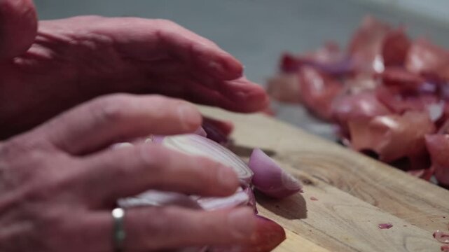 Stockholm, Sweden A cook cuts and peels shallots or onions on a wooden board with a large knife. 