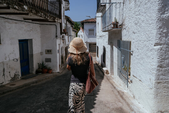 Middle aged expat seen from behind walking alone through small Spanish village