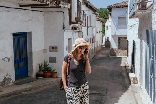 Smiling Mature Woman Talking on Smartphone While Exploring a Spanish Village