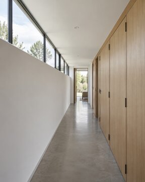 A long clerestory window lights a narrow corridor beside flush timber storage doors, bringing daylight into the depth of a quiet residential plan