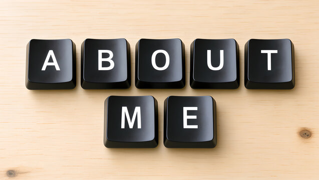 About Me text spelled out with black computer keyboard keys on wooden surface.