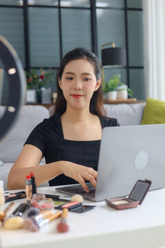 Young woman beauty blogger streaming makeup tutorial with ring light and smartphone.