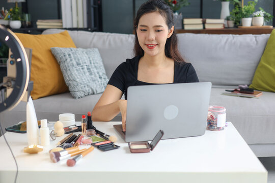 Young woman beauty blogger streaming makeup tutorial with ring light and smartphone.