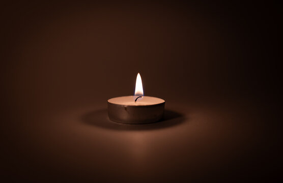 Small tea light candle burning in dark background