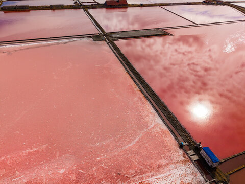 Salt extraction takes place in broad evaporation ponds divided by narrow causeways at a salt works