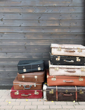 Vintage Suitcases Stacked Against Gray Wooden Wall