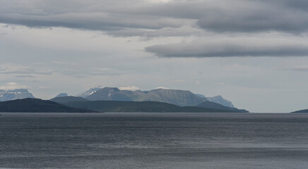 Minimalist view of open arctic fjord waters and distant mountain silhouettes under overcast sky near Gildetun, Norway © LAURA