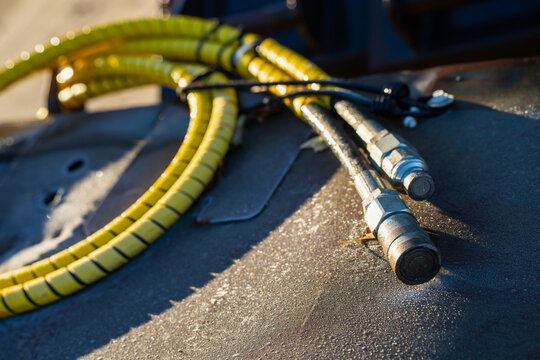 Hydraulic hoses terminate in metal quick release couplings beside spiral protective guards, illustrating detachable fluid connections for equipment attachment handling and service