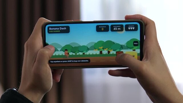 Person plays a colorful side-scrolling mobile game on a smartphone, collecting items and avoiding obstacles as casual gaming and mobile entertainment continue to grow.