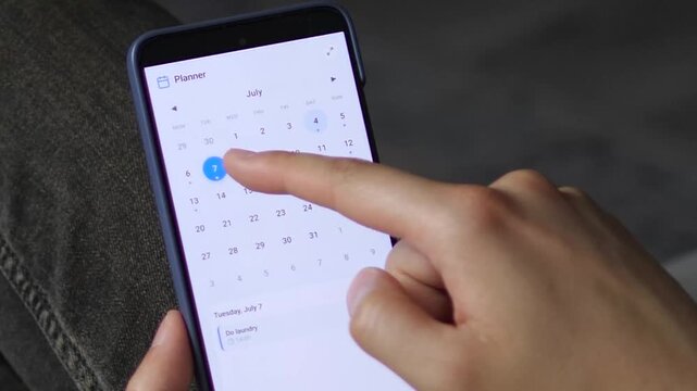Person uses a mobile calendar planner to review daily tasks and appointments, highlighting digital productivity, time management and organized routines on a smartphone.