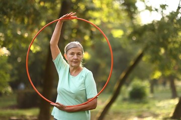 Senior woman with hula hoop in park, space for text © New Africa