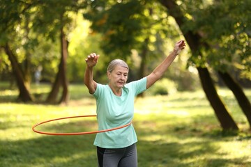 Senior woman exercising with hula hoop outdoors © New Africa