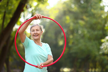 Senior woman with hula hoop in park, space for text © New Africa