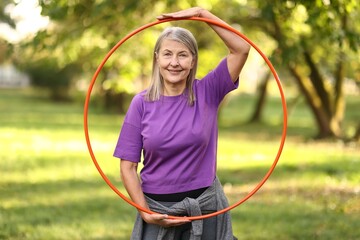 Senior woman with hula hoop in park © New Africa