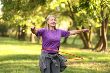 Senior woman exercising with hula hoop outdoors © New Africa