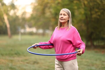 Senior woman exercising with hula hoop outdoors © New Africa