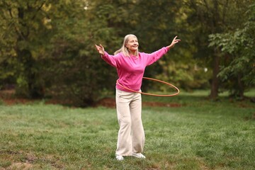 Senior woman exercising with hula hoop outdoors © New Africa