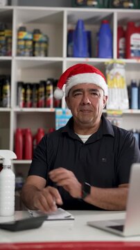 Auto shop owner wearing santa hat talking on video call in store