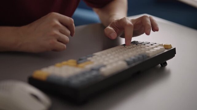 Closeup of man hands typing on customized mechanical keyboard with retro style keycaps, showing fingers pressing keys working at desk in home office setup. Shooting in slow motion.