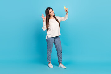 Full body photo of young cheerful lady talk mobile wave greetings conversation isolated over blue color background © deagreez