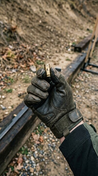 Hand holding a spent bullet casing at an outdoor shooting range close up