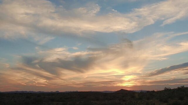 Dramatic sunset over desert landscape with scattered clouds