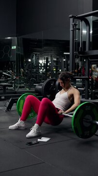 Woman doing barbell hip thrusts, vertical video
