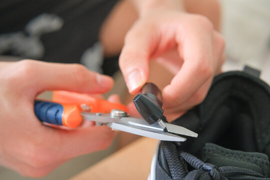 Removing an anti-theft security tag from sneakers with pliers, closeup of hands cutting a retail security attachment on footwear