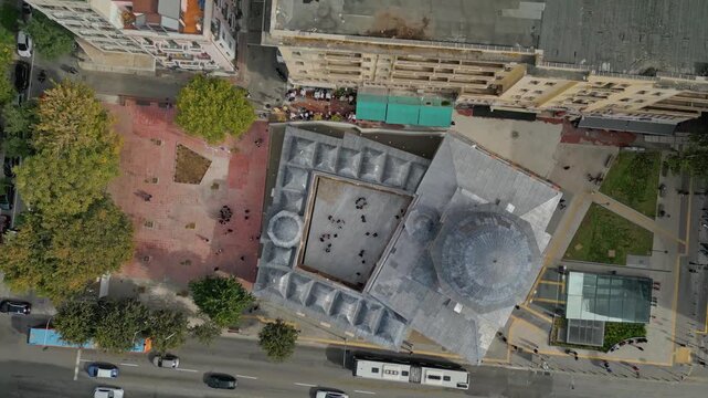 Cinematic 16:9 aerial video, shot in smooth 60fps, showing a top-down rotating view of the restored Hamza Bey Mosque, also known as Alkazar, in Thessaloniki.