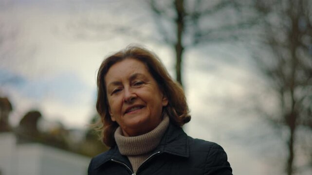 Happy Caucasian senior woman smiling outdoors under trees and sky