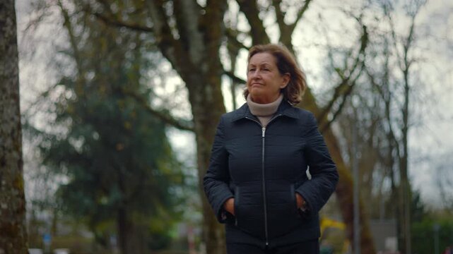 Caucasian retiree walking slowly through the park and looking around