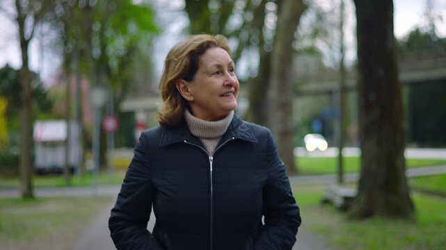 Caucasian senior woman walking on a tree-lined park path